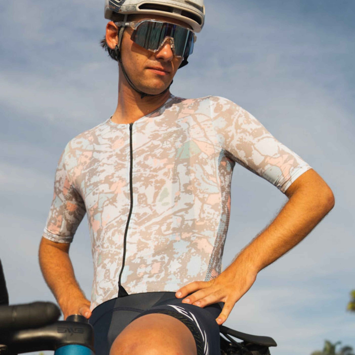 Male cyclist standing on bike in multicolor jersey