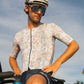 Male cyclist standing on bike in multicolor jersey
