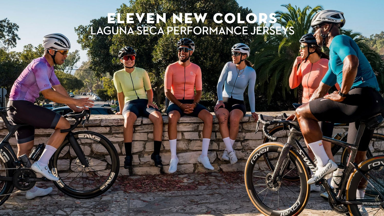 A group of cyclists in colorful solid jerseys sititng on wall and on bikes. 